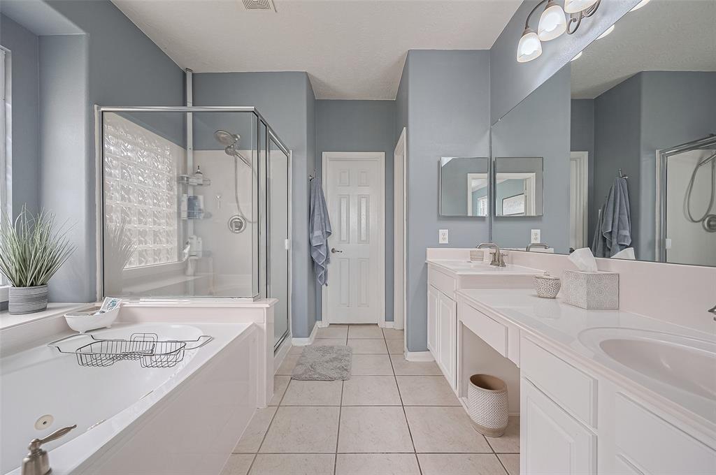 The primary bath is a serene retreat featuring dual vanities, a soaking tub, a glass-enclosed shower, and generous storage.