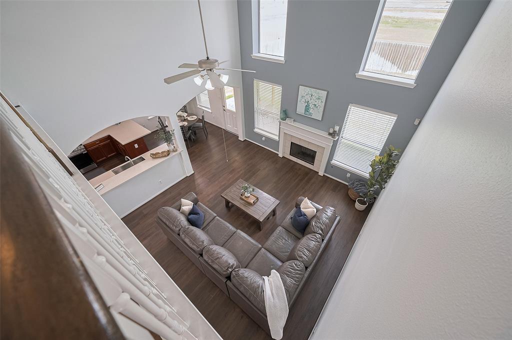 The dramatic two-story living room offers a stunning view from the second floor, with abundant windows and a fireplace as the focal point.