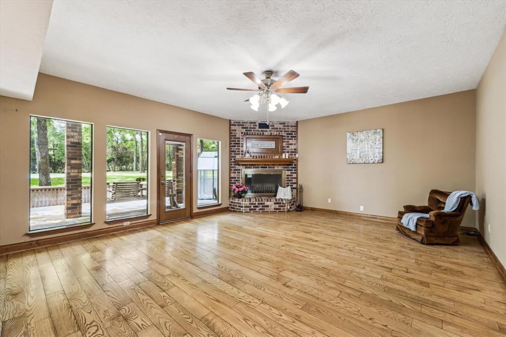 Another view of the living area without some of the furniture, showcasing the natural wood flooring.