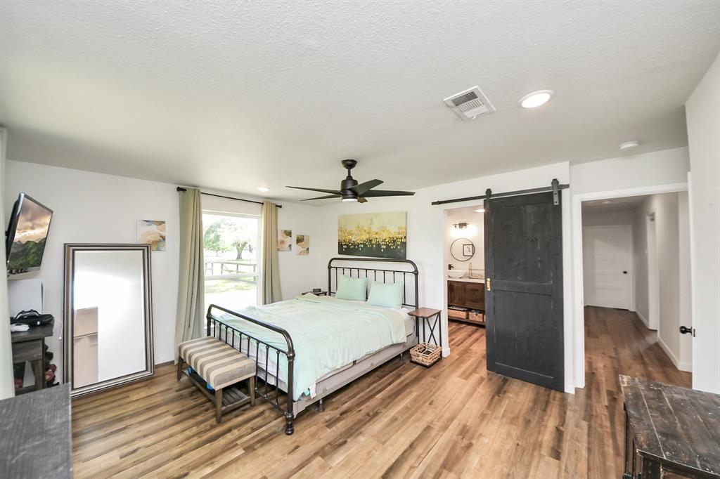 Cozy and stylish primary bedroom featuring a sliding barn door that opens to an updated, private en-suite bath.
