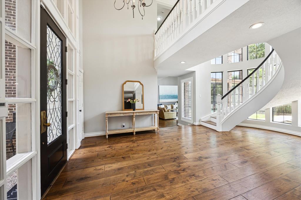 This elegant entryway features a grand staircase, high ceilings, and abundant natural light. The hardwood floors and wrought iron door add sophistication, while the open design provides a welcoming feel.